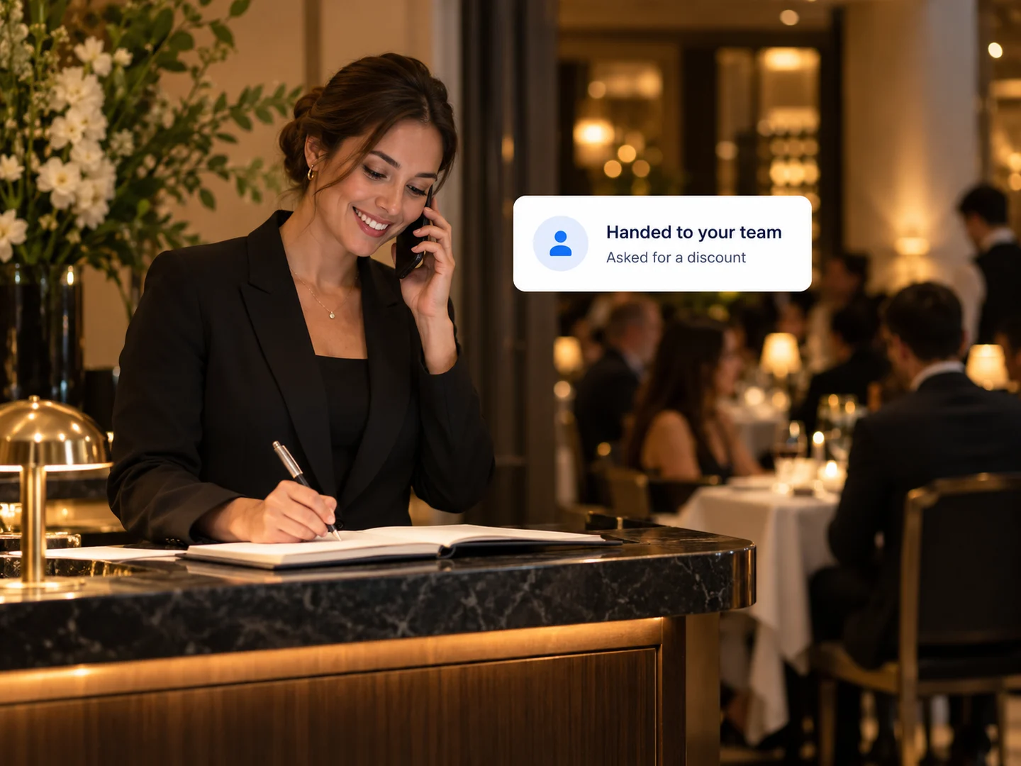 An events manager taking a call at the host stand after an inquiry was handed to the team