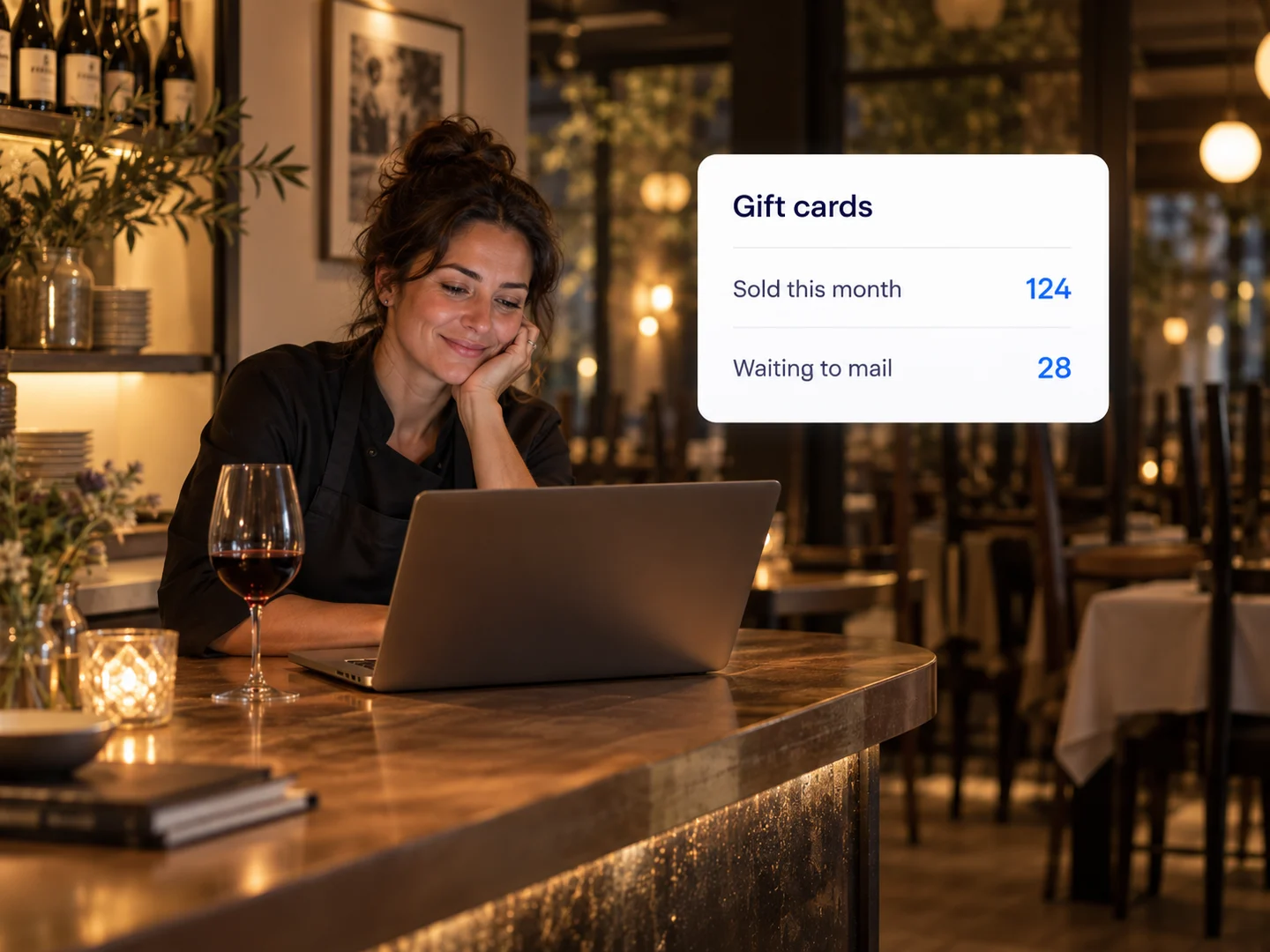 A restaurant owner at the bar after close checking gift cards sold and waiting to mail
