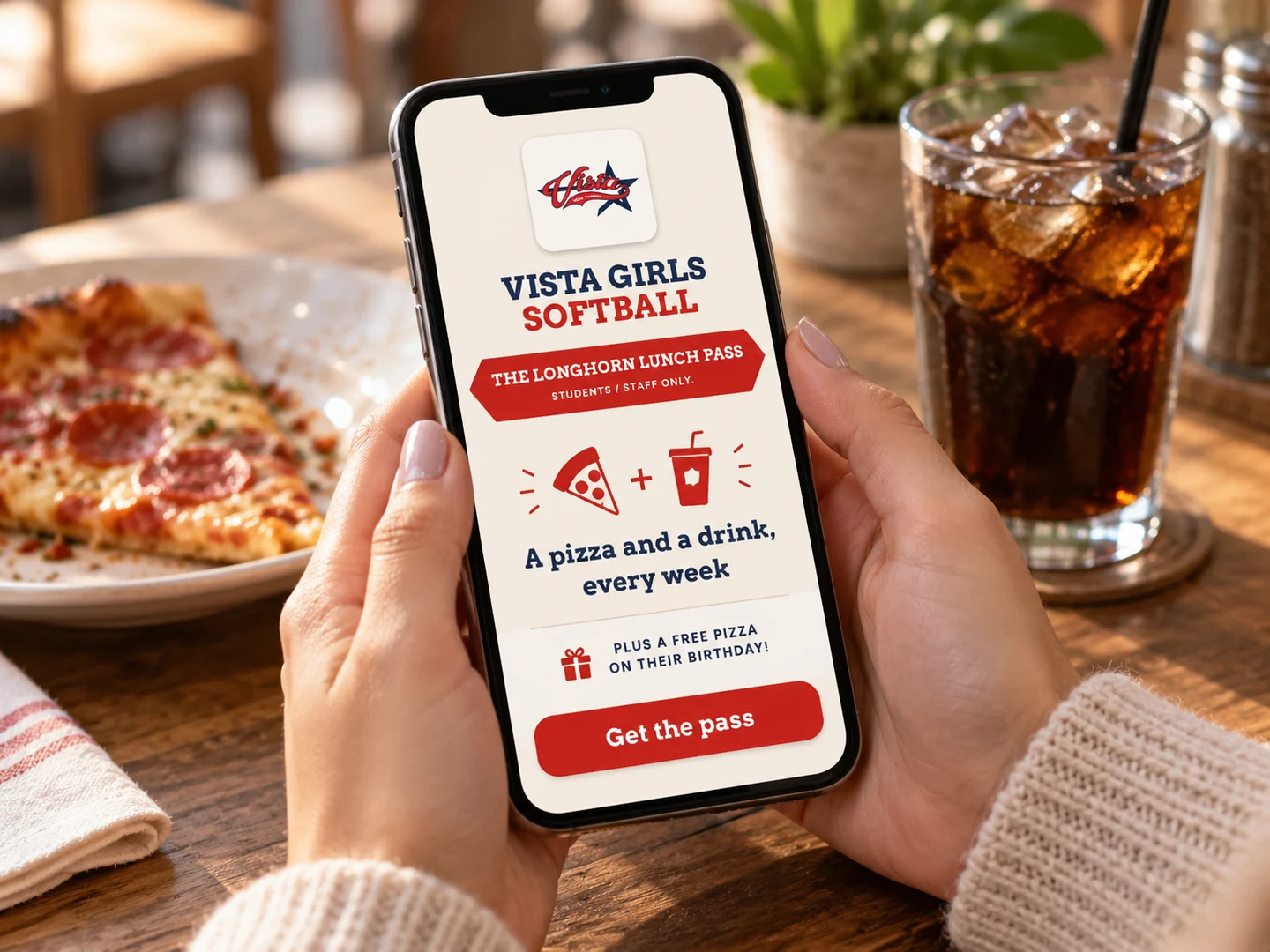A guest holding a phone showing a lunch pass for a pizza and a drink every week